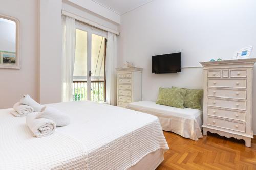 a white bedroom with two beds and a dresser at Villa Antiope Saronida in Saronida