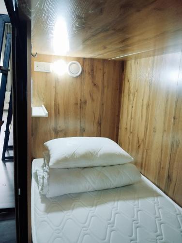 a bed in a room with a wooden wall at Salma Capsule Hostel in Bishkek