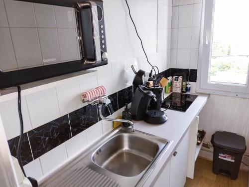 a kitchen with a sink and a microwave at Le Sympathique - Petit Déjeuner, Netflix, Jacuzzi in Rouen