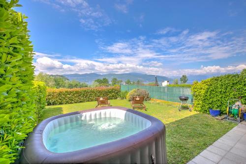 un patio trasero con una bañera de hidromasaje en el césped en Miralago Lake View Outside Whirlpool - Happy Rentals en Ispra