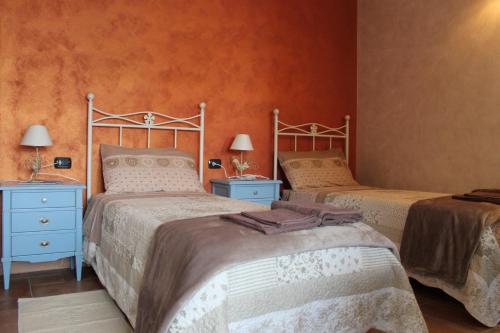 2 letti in una camera da letto con pareti arancioni di B&B la Pavoncella a Villamar
