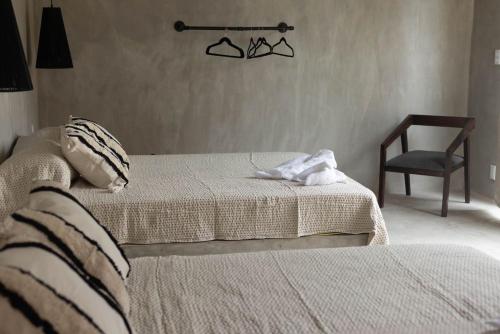 a bedroom with two beds and a chair and a chair at Naari Cabañas Boutique in Brisas de Zicatela