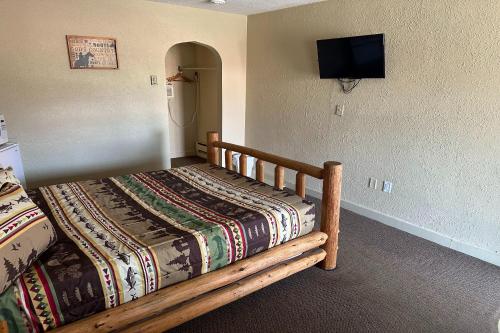 um quarto com uma cama de madeira e uma televisão na parede em Love Hotels Murdo on Interstate 90 em Murdo