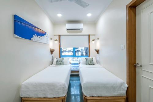 a room with two beds and a window at Hotel Kemps Corner in Mumbai