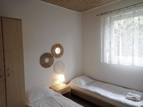 two beds in a room with a window and a lamp at Domy Nad Zalewem in Dziwnówek
