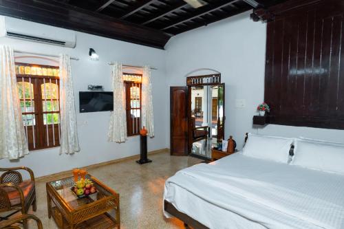 a bedroom with a bed and a table and a tv at Brookside Heritage Resort in Kumarakom