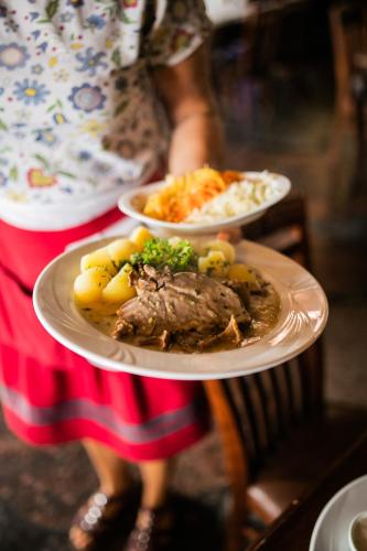 a person holding two plates of food on a table at Nordowi Dwór in Celbowo