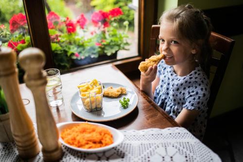a little girl sitting at a table eating food at Nordowi Dwór in Celbowo
