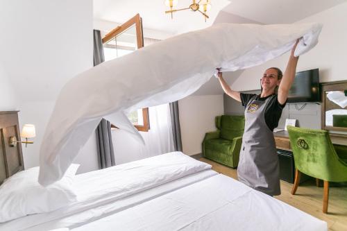 a woman holding up a white sheet over a bed at Nordowi Dwór in Celbowo