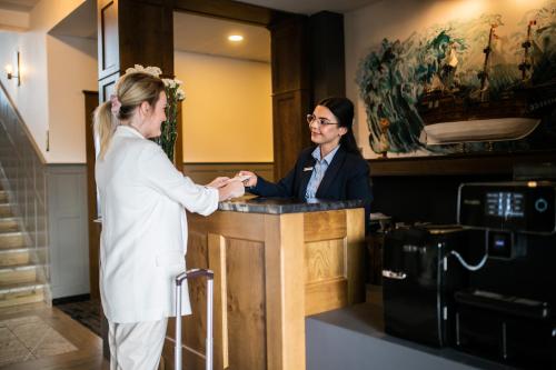 a woman shaking hands with a woman at a counter at Nordowi Dwór in Celbowo