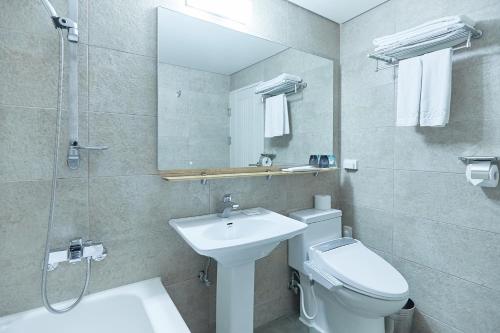 a bathroom with a sink and a toilet and a mirror at Towerhill Hotel in Busan