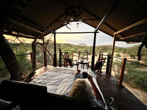 a woman laying on a bed in a tent with a view at Ondudu Safari Lodge in Omaruru