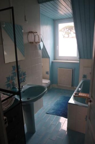 La salle de bains est pourvue d'un lavabo, d'une baignoire et d'une fenêtre. dans l'établissement Appartement avec vue sur mer, à Carantec