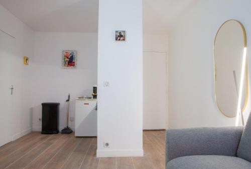 a living room with a chair and a mirror at Confortable Studio proche Paris et Eurodisney in Villemomble