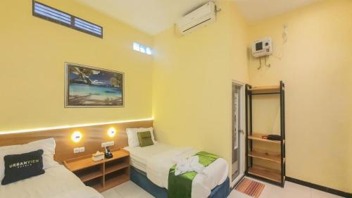 a hotel room with two beds and a mirror at Urbanview Hotel Sakura Kampung Inggris Pare by RedDoorz in Pare