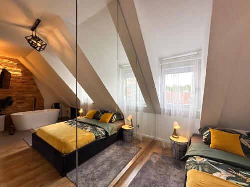 a attic bedroom with two beds and a bath tub at Apartament Zielone Fotele Starówka in Olsztyn