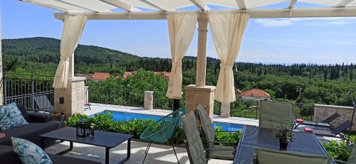 a patio with a view of a pool and a house at Villa Lucija Cilipi in Čilipi