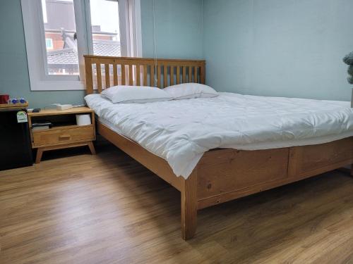a bed with white sheets and pillows in a bedroom at Son-Gil Guesthouse in Jinju