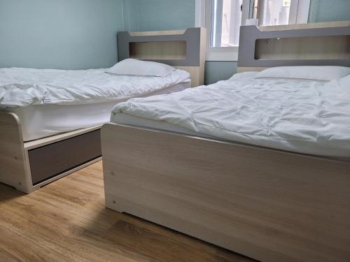 two beds sitting next to each other in a room at Son-Gil Guesthouse in Jinju