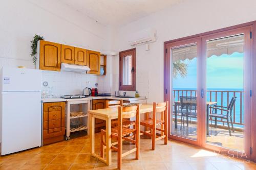 Il comprend une cuisine équipée d'un réfrigérateur blanc et d'une table avec des chaises. dans l'établissement Amphitriti SeaFront Apartments, Loutra Agia Paraskevi, à Agia Paraskevi
