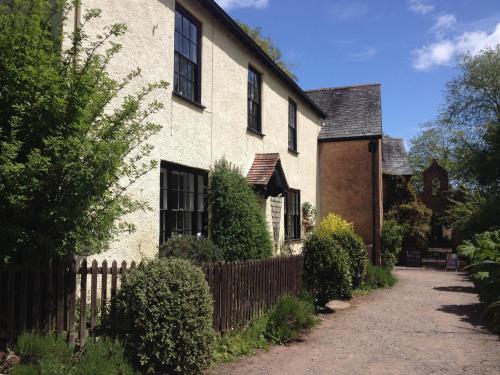 a white house with a fence next to a driveway at Dunster Mill House in Dunster