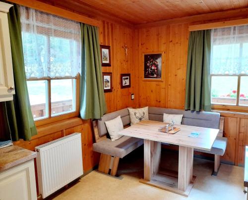 a dining room with a table and chairs and windows at Hallmoosgut in Sankt Johann im Pongau