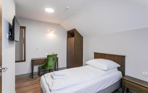 a bedroom with a bed and a desk with a green chair at Nordowi Dwór in Celbowo