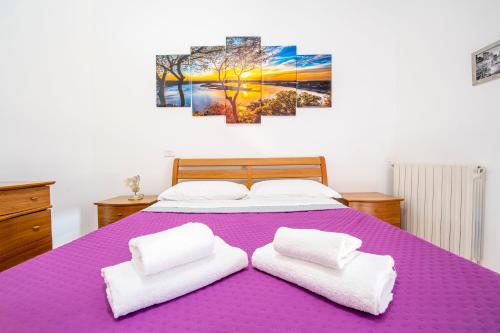a bedroom with a purple bed with two white towels at Casa Fontanini in Rome