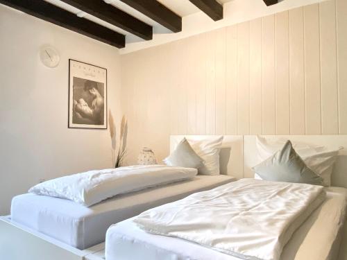 two beds in a bedroom with white sheets and pillows at *Schwarzwald-Apartment 2° * in Elzach