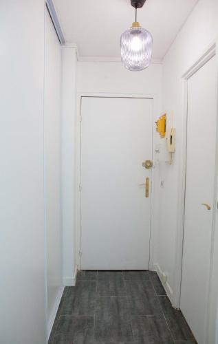 un couloir avec une porte blanche et une lampe dans l'établissement Studio Lumineux proche de Paris et Disneyland, à Villemomble