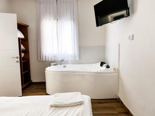 a white bath tub in a room with a television at Etzel Tami Hospitality in Neot Golan