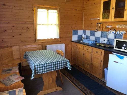 una cocina con mesa en una cabaña de madera en Álmos Apartman, en Balatonfenyves