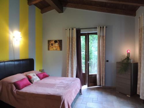 um quarto com uma cama com lençóis cor-de-rosa e uma janela em B&B CASA BELLA COMBA em Vignolo