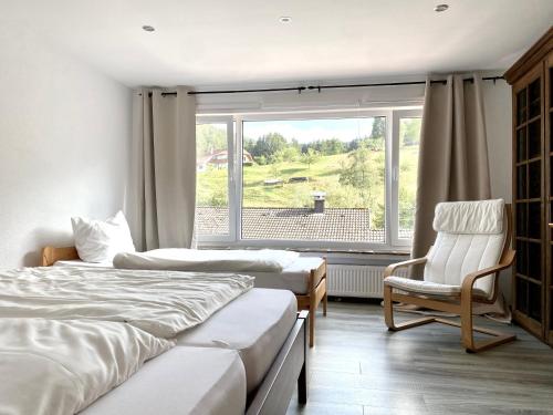a bedroom with two beds and a chair and a window at *Schwarzwald-Apartment 1° * in Elzach