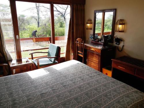 Schlafzimmer mit einem Bett, einem Schreibtisch und einem Fenster in der Unterkunft Seronera Wildlife Lodge in Serengeti-Nationalpark