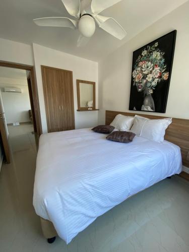 a bedroom with a large white bed with a ceiling fan at Larnaca Bay Suites in Larnaka