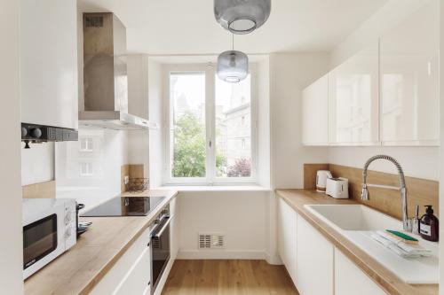 une cuisine blanche avec un évier et une fenêtre dans l'établissement Le Nuage Malouin - Appt à 300m de la plage, à Saint-Malo