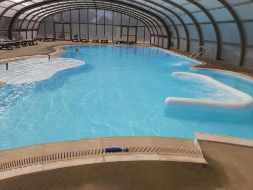 - une grande piscine dans un bâtiment d'eau bleue dans l'établissement Cottage, à Jullouville