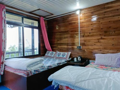 Duas camas num quarto com uma parede de madeira em Hosanna homestay em Darjeeling