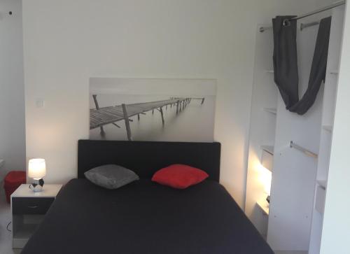 - une chambre avec un lit noir et des oreillers rouges dans l'établissement Belle Maisonnette avec jardin 2 pas du VIEUX PORT, à La Rochelle