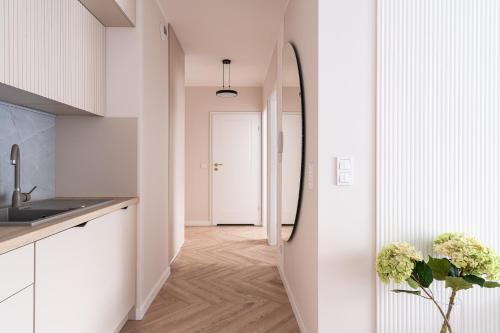 una cucina con pareti bianche e un corridoio con specchio di RentPlanet - Nowa Manufaktura a Breslavia