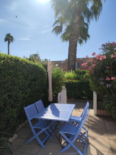 une table bleue et des chaises sur une terrasse avec un palmier dans l'établissement Villa Club T2 à Mar Vivo, plages à pieds, piscine, à La Seyne-sur-Mer