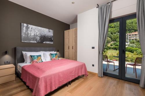 a bedroom with a bed with a pink blanket at PERUNIKA BED & BREAKFAST in Mošćenička Draga