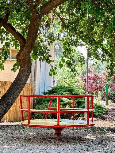 a red bench under a tree next to a building at Etzel Tami Hospitality in Neot Golan