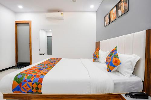 a bedroom with a large white bed with colorful pillows at FabHotel Magnus in Surat