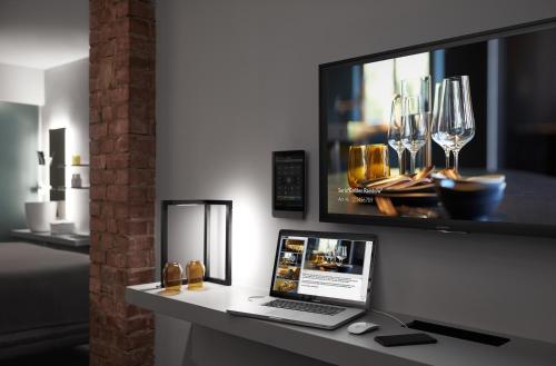 a laptop on a desk with a tv and wine glasses at Mittermeiers Alter Ego in Rothenburg ob der Tauber