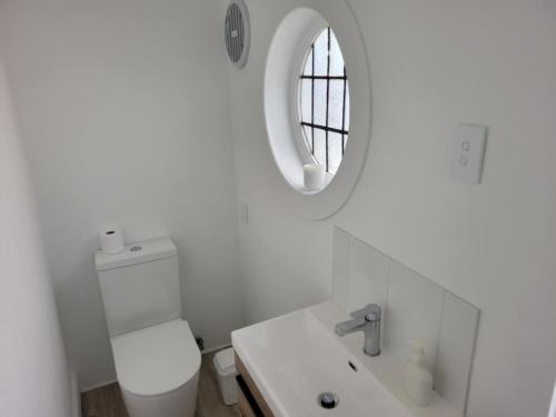 a white bathroom with a sink and a mirror at 1920s Classic Cozy 2-Bedroom Villa Apartment in Parnell in Auckland