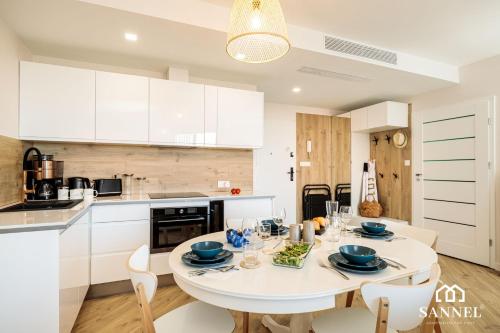 a kitchen and dining room with a white table and chairs at Apartament Premium Sea-Pinea Apartments Pobierowo in Pobierowo