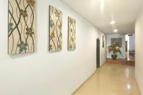 a hallway with four paintings on a wall at Urbanview Hotel Mulia Indah Palopo in Palopo