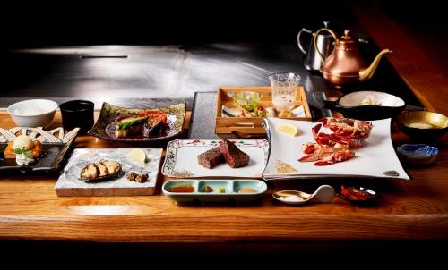 a wooden table with plates of food on it at Garden Terrace Saga Hotel & Resorts in Saga
